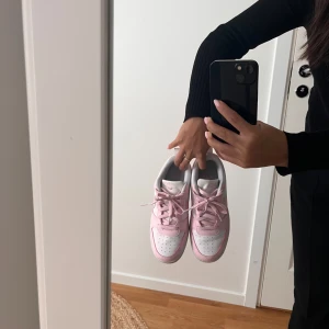 Nike Dunk Low rosa och vita sneakers - Nike Dunk Low sneakers i en fräsch kombination av ljusrosa och vitt. Säljer då dom inte kommer till användning. Har bara använt 2 gånger. Strl 38 säljer för 450 kr vid snabb affär kan priset diskuteras 