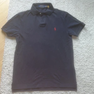 Mörkblå pikétröja från Ralph Lauren - Säljer en mörkblå pikétröja från Polo Ralph Lauren i slim fit. Tröjan är knappt använd i och är i toppen skick, 9,5 av 10. 
