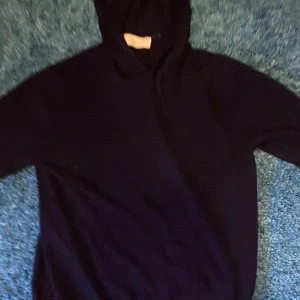Mörkblå hoodie i kashmir från Sayless - Mysig svart hoodie från Sayless i lyxig kashmir. Tröjan har huva och långa ärmar, perfekt för dig som gillar en stilren och enkel look. Passar dig som vill ha något både bekvämt och snyggt till vardags.