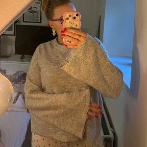 stickad tröja med vida ärmar - Mysig grå stickad tröja med riktigt vida och långa ärmar. Perfekt för dig som gillar en chill och oversized look. Tröjan har en enkel design utan mönster och är superenkel att matcha med allt.