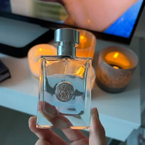 Versace Pour Homme Eau de Toilette - Versace Pour Homme Eau de Toilette med elegant, transparent glasflaska och silverdetaljer. Flaskan har Versaces ikoniska Medusa-logga framtill och ett stilrent, maskulint uttryck. Kommer med original mörkblå kartong med silvertext och mönster. Perfekt för dig som gillar lyxiga dofter.