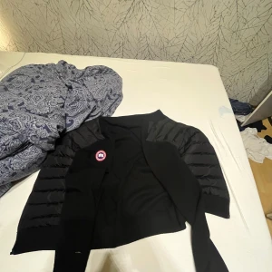 Svart cardigan jacka från Canada Goose - Jag säljer min Svart cardigan jacka som inte är andvänd pga att den inte passar Tyvärr så funkar inte kjedjan men det går och fixa i någon butik annars är den mycket bra skick andvänd 5 gånger minst inga skador på den.