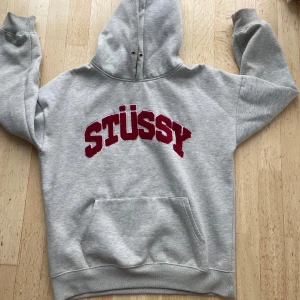 Grå Stüssy hoodie med röd logga - Snygg grå hoodie från Stüssy, är storlek L men sitter mer som M