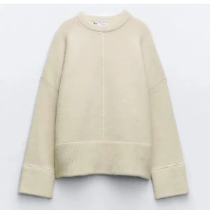Beige stickad tröja från Zara - Supermjuk beige stickad tröja från Zara med oversized passform och markerad söm framtill. Tröjan har breda muddar vid ärmslut och nederkant samt rund halsringning. Perfekt för lager-på-lager under kyliga dagar.