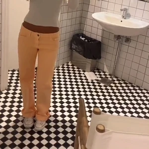 Persikofärgade raka jeans - Säljer ett par persikofärgade jeans med rak passform och låg midja. Byxorna har klassisk femficksdesign och stängs med knapp och dragkedja. Materialet är bomull med lite stretch. Höger bakficka har en speciell design. Midjemått: 38. Benen är långa men går att vika upp samt att vika ner.