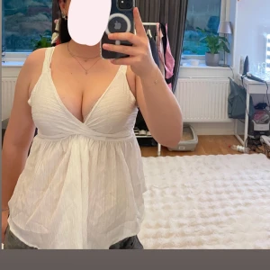 Vit omlott linnetopp med rosett - Supersöt vit linnetopp med omlott-skärning och djup v-ringning. Toppen har breda axelband och en knytrosett i ryggen. Använd en gång💗 