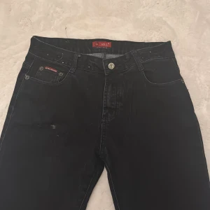 Svarta jeans med broderi och nitar - Snygga svarta jeans från H&L Jeans med raka ben och coola broderade detaljer samt små nitar på bakfickorna och linningen. Klassisk femficksmodell i jeansmaterial, perfekt för dig som gillar en stilren look med en twist.