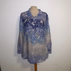 Två tunna skjortor med tryck - Säljer två tunna skjortor i längre modell. Ena är blå med vitt grafiskt mönster och knappar framtill, den andra är svartgrå med abstrakt mönster och asymmetrisk nederkant. Båda har lång ärm och är gjorda i ett lätt, transparent material. Den grå är i storlek 34 och från H&M, den blå saknar lapp. Den grå har även en liten defekt (se bild)