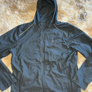  Under Armour vindjacka  - Svart vindjacka från Under Armour med huva och hel dragkedja. Jackan har reflekterande detaljer vid axlarna, meshfoder och logga på bröstet samt stort tryck på ryggen. Perfekt för träning utomhus när det blåser. Pris går att prutas ner vid snabb affär!!💨