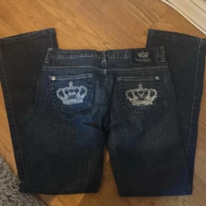Säljer ett par jätte snygga Victoria Beckham jeans !!! Jag är 1,70cm och storleken är w28 - Jätte snygga mörkblå jeans från Victoria Beckham med utsvängda ben och snygga broderade kronor i silver på bakfickorna. Jeansen är tillverkade i 100% bomull och har klassisk femficksdesign. Perfekta för dig som vill sticka ut med coola detaljer.