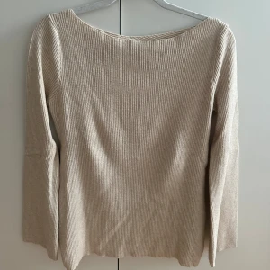 Beige ribbad med omlott baktill - Supersnygg beige ribbad tröja med lång ärm och omlottdetalj baktill. Passar dig som gillar stilrena och enkla plagg med en twist. Enkel att matcha med både jeans och kjol