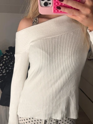 Vit ribbad offshoulder stickad tröja - Säljer en vit stickad tröja med ribbad struktur och oneshoulder . Aldrig använd❣️❣️ 