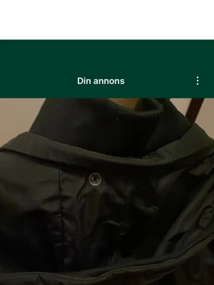 Svart vindjacka från Lindex, storlek L - Svart vindjacka från Lindex i storlek L med huva och dragkedja framtill. Jackan har en enkel design med knappdetaljer och är tillverkad i polyester, perfekt för blåsiga dagar. Snygg och praktisk att slänga på sig när det är ruggigt ute. Säljs på fler sidor. Köparen betalar frakt.