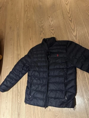 Blå pufferjacka från Polo Ralph Lauren - Säljer en blå pufferjacka från Polo Ralph Lauren.  Mycket fint skick- som ny! Nypris 4200 kr