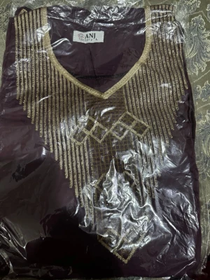 Lila blus med guldbroderi från GANJ - Säljer en lila blus från GANJ i storlek L med detaljerat guldbroderi framtill. Blusen har v-ringad hals och broderade geometriska mönster i guld längs bröstet och sidorna. Materialet känns mjukt och lätt, perfekt för dig som gillar unika detaljer.