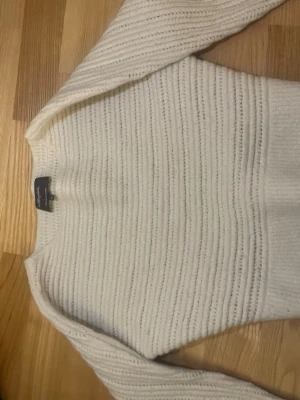 Vit ribbad stickad tröja Lexington - Säljer en vit stickad tröja från Lexington med ribbad struktur och rund hals. Tröjan har långärmade ärmar och är gjord i mjukt material som passar perfekt för kyliga dagar. Enkel och stilren design som är lätt att matcha med jeans eller kjol.