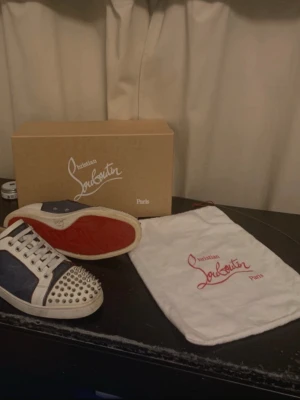 Christian Louboutin skor - Säljer ett par Christian Louboutin skor i vitt och mörkblått. Kommer med originalkartong och dustbag. De säljs då jag fick ett nytt par skor. Bra skick och priset kan diskuteras. Hör av dig via minsta fråga!