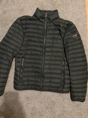 Olivgrön jacka från Colmar - Säljer en olivgrön jacka från Colmar Originals i storlek 50. Jackan har quiltad design, två sidofickor med dragkedja och hög krage. Materialet är syntet och jackan har en Colmar-logga på ärmen. Perfekt för kyliga dagar och har en clean, modern look.