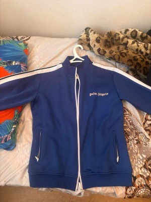 Palm angels zip - En fin mörkblå palm angels tracksuit top. Vita ränder på sidan inget fel på tröjan den är i använt skick. Storlek L men passar M.Tveka ej att höra av er vid prisförslag eller frågor.