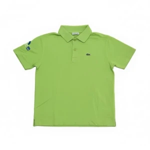 Grön piké från Lacoste - Snygg grön pikétröja från Lacoste med klassisk krage och två knappar framtill. Tröjan har korta ärmar och ett litet Lacoste-logotyp broderat på bröstet. Materialet är mjukt och känns sportigt, perfekt för en avslappnad stil.
