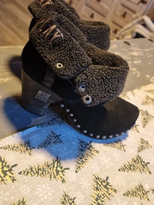 Svarta stövletter från Replay med päls - Säljer ett par svarta stövletter från Replay med grov pälsimitation upptill och snygga nitar längs sulan. Klacken är robust och i trälook, och skorna har Replay-logga på både häl och skaft. Materialet är mocka och pälsimitation, perfekt för dig som gillar detaljer.