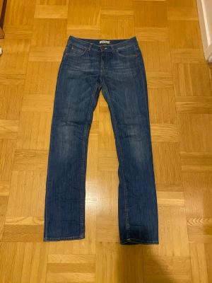 Blå Acne Jeans Hex Lena 30/32 - Snygga blå jeans från Acne Jeans, modell Hex Lena i storlek 30/32. Klassisk femficksdesign med raka ben och normal passform. Materialet är 98% bomull och 2% elastan för lite stretch. Perfekta för dig som gillar stilrena och tidlösa jeans.