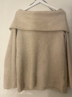 Beige offshoulder stickad tröja H&M - Säljer en beige stickad tröja från H&M i storlek XS. Tröjan har en bred offshoulder-krage och är ribbstickad med långa ärmar. Perfekt för dig som gillar en chill och cozy stil under höst och vinter.
