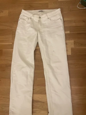 Vita raka jeans från Stay, storlek S - Säljer ett par vita jeans från Stay i storlek S. Byxorna har klassisk femficksmodell, raka ben och normal passform. Tillverkade i bomull med snyggt silverfärgat knappdetalj fram. Perfekta till en clean och fräsch look.