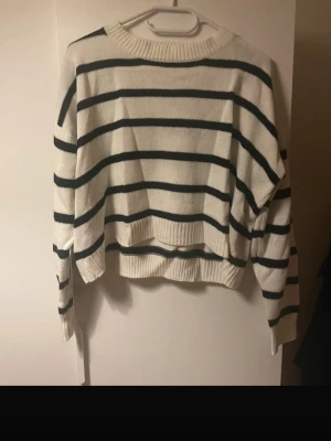 Randig stickad tröja från SHEIN - Säljer en vit och svart randig stickad tröja från SHEIN i storlek S. Tröjan har en loose passform, långa ärmar och ribbad kant vid hals, ärmslut och nederkant. Perfekt för dig som gillar en chill och avslappnad stil.