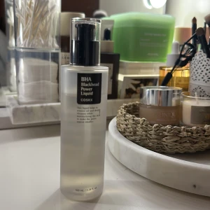COSRX BHA Blackhead Power Liquid - Transparent toner i en stilren plastflaska med svart pump, 100 ml. Innehåller BHA som hjälper till att ta bort olja och rengöra porerna på djupet samtidigt som huden återfuktas. Perfekt för dig som vill ha en fräsch och klar hud.