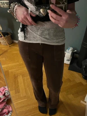 Juicy couture byxor - Bruna mjukisbyxor från Juicy Couture i mjuk sammet med raka ben och snörning i midjan. Framtill finns två stora fickor och baktill två fickor med knapp. Perfekta för chill dagar och har en snygg, enkel design.