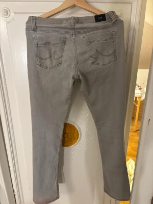 Grå bootcut jeans från LTB  - Säljer ett par grå jeans från LTB med bootcut-snitt. Byxorna har fem fickor, låg midja och klassisk jeansdesign med synliga sömmar och bälteshällor. Materialet är mjukt denim i bomull och passformen är normal. Perfekt för dig som gillar stilrena och enkla jeans.