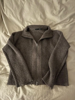Brun ribbad kofta från 157 - Säljer en brun ribbstickad kofta från 157 i storlek XS. Koftan har långärmade ärmar, krage och hel dragkedja framtill. Materialet är stickat och känns mjukt och mysigt. Använd 1 gång 🤎
