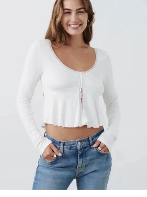 Vit blus  - Slutsåld topp från Gina Tricot. Toppen har spetsdetaljer längs halsringningen och framtill, en liten rosett och öppen vid magen. Aldrig används men har ej prislappen kvar 