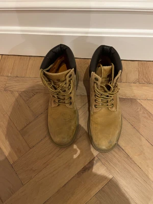 Beige boots från Lumberjack - Säljer ett par klassiska beige boots från Lumberjack med rund tå och snörning. Skorna har en robust platt sula och är tillverkade i skinn med vadderad svart krage upptill för extra komfort. Perfekta för höst och vinter, snygga till jeans och jacka.