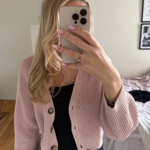 Ljusrosa kofta från Monki XS - Ljusrosa kofta från Monki som är stickad stickad. Modellen har stora knappar framtill och har långärmade, lite bredare ärmar.