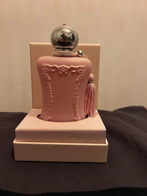 Parfums de Marly Delina 75ml - Delina från Parfums de Marly är en lyxig Eau de Parfum i en snygg rosa flaska med silverdetaljer och tofs. Volymen är 75 ml och den är tillverkad i Frankrike. Perfekt för dig som vill sticka ut med en exklusiv doft.