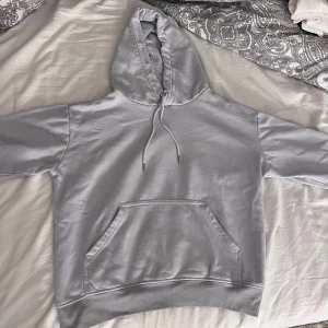Gråblå hoodie från Hm - Säljer en gråblåa hoodie från H&M i storlek S. Tröjan har huva med snörning, stor magficka och ribbade muddar vid ärmslut och nederkant. Lite färgförändring vid de ribbade kanterna! 🩷