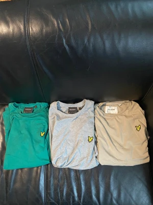 3-pack Lyle & Scott t-shirts i olika färger - Säljer tre snygga t-shirts från Lyle & Scott i färgerna grön, grå och beige. Alla har klassisk passform, korta ärmar och den ikoniska gula örnloggan broderad på bröstet. Perfekta för en clean och stilren look. Materialet är mjuk bomull. Nypris 900, mitt pris 499