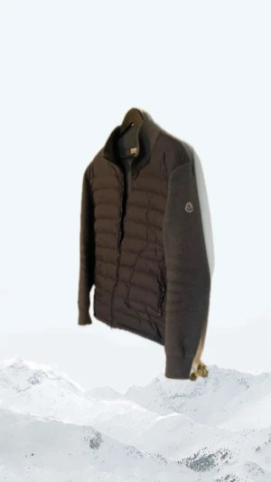 Grå Moncler cardigan jacka - Snygg grå cardigan jacka från Moncler med quiltad front och ärmar i stickad bomull. Jackan har dragkedja framtill, Moncler-logga på ärmen och en clean, modern look. Perfekt för dig som vill ha något stilrent och bekvämt. Storlek L men passar m
