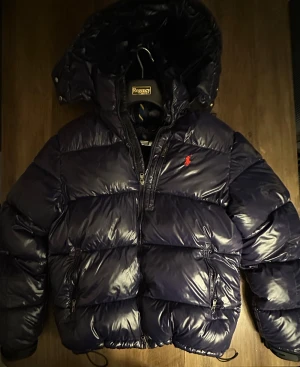 Mörkblå pufferjacka Polo Ralph Lauren - Mycket fint skick, inga defekter. Storlek 46/48/S passar dig som är mellan 170-185cm. Nypris ca 6000kr och kan verifieras med qr koden! Modellen ar 180cm, 70 kg. Passar bra nu till vintern! Pris kan diskuteras skriv för mer information🤝