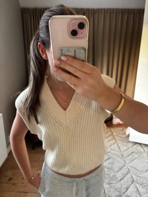 Krämvit stickad croppad topp - Säljer en krämvit stickad topp med v-ringning och bred ribbad kant. Modellen är croppad och kan bäras både med axlarna uppe eller offshoulder. Materialet är mjukt och stickat, perfekt för dig som gillar en chill och trendig look.