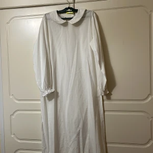 Vit långklänning med krage från Lindex - Vit lång klänning till Lucia tåget den är perfekt till ett barn som är 10-12 år. Den är från Lindex och har bara använt den en gång. Det är en liten fläk med stearinljus som har droppat på kanten men det går bort. 