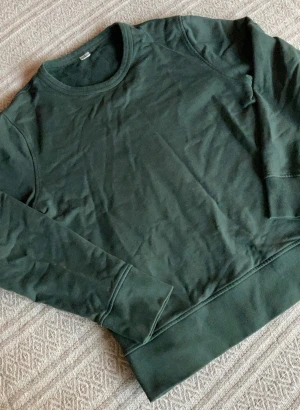 Sweatshirt från ARKET - En stilren mörkgrön sweatshirt från ARKET i storlek S, tillverkad av 100% ekologisk bomull. Tröjan har rund hals, långa ärmar och breda muddar vid ärmslut och nederkant. Perfekt för chill dagar och enkel att matcha med jeans eller joggers.