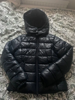 Mörkblå pufferjacka med avtagbar huva - Säljer en mörkblå pufferjacka med avtagbar huva och dragkedja framtill. Jackan har två snedställda fickor med dragkedja och quiltad design. Perfekt för kalla dagar och riktigt skön att bära. Passformen är normal och jackan är lätt vadderad. Den är perfekt nu till vinter när det blir så kallt utomhus!🤍❄️