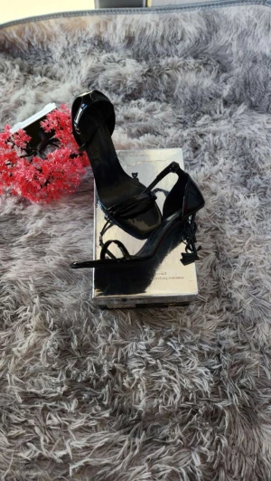 Svarta klackade med YSL-detalj - Snygga svarta  med hög klack och ikonisk YSL-logga som klackdetalj. Skorna har smala remmar och öppen tå, tillverkade i glansigt syntetmaterial. Perfekta för dig som vill sticka ut med en lyxig och trendig look.