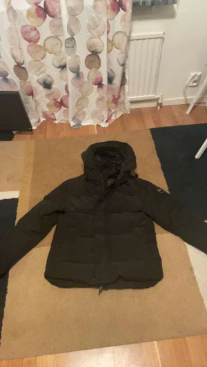 Svart dunjacka Canada Goose L - Säljer en svart dunjacka från Canada Goose i storlek L. Jackan har huva, dragkedja och klassisk patch på ärmen. Perfekt för kalla dagar med sin rejäla fyllning och stilrena look. Passar dig som vill ha både värme och streetstyle. Kommer med NFC