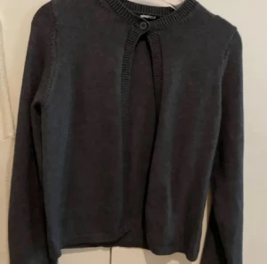 Mörkgrå kofta från Gina Tricot - Snygg mörkgrå kofta från Gina Tricot med rund hals och knappdetalj upptill. Endast använd 2 ggr. Super bra skick 