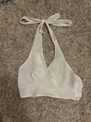 Vit omlott linnetopp med knyt - Säljer en  vit linnetopp från Bershka med omlott-design och breda knytband både i nacken och runt midjan. 
