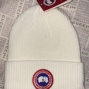 Canada goose vaniljvit mössa  - Helt ny Canada goose vintermössa i rött märke.mycket fin mössa speciellt i person. Onesize / unisex Finns i Göteborg annars frakt som alternativ.färgen är cream white se sista bilden. 